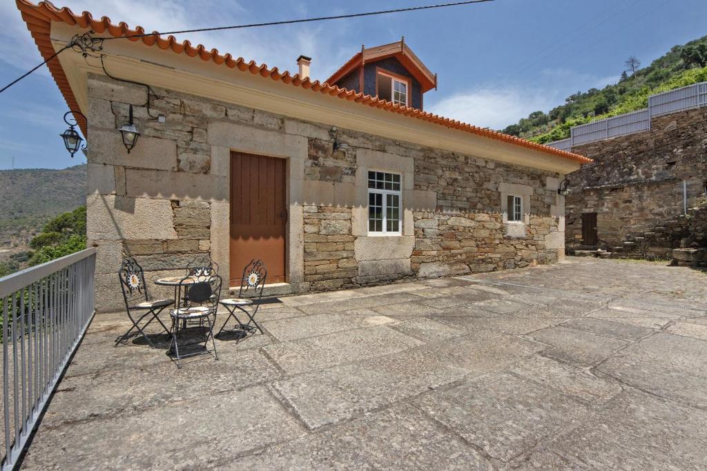 a stone house with two chairs and a table on a patio at Casa Do Riacho - Douro in Armamar