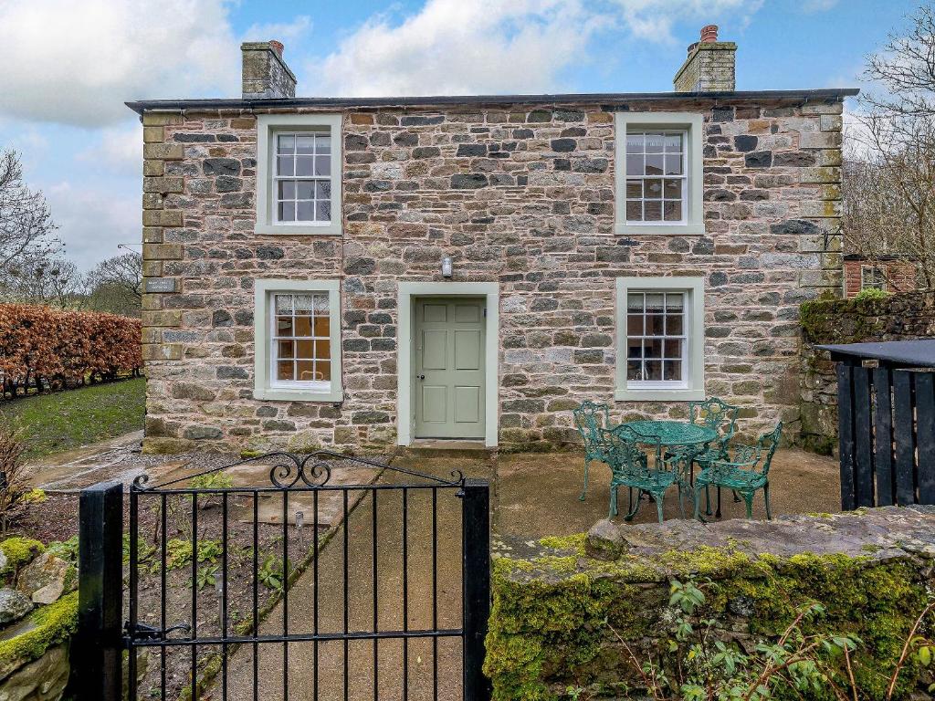 an old stone house with a green door and a table and chairs at Branthwaite Cottage in Caldbeck