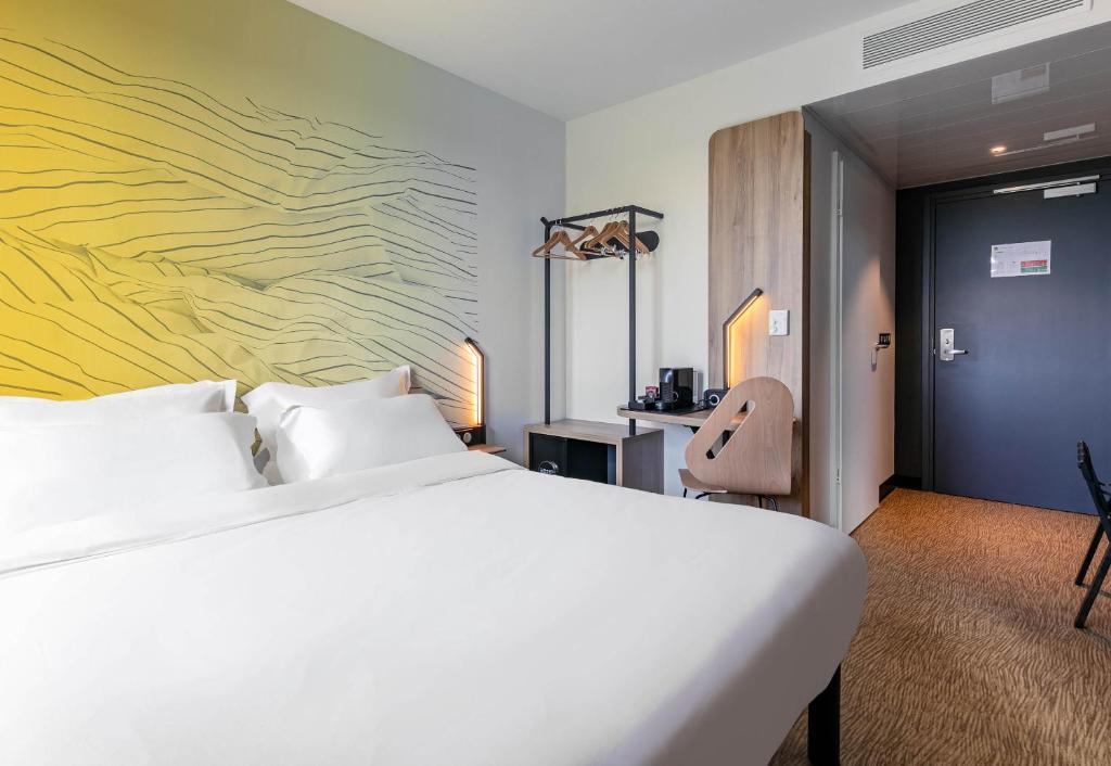 a bedroom with a white bed and a yellow wall at B&B HOTEL Mulhouse Bâle Aéroport in Hésingue