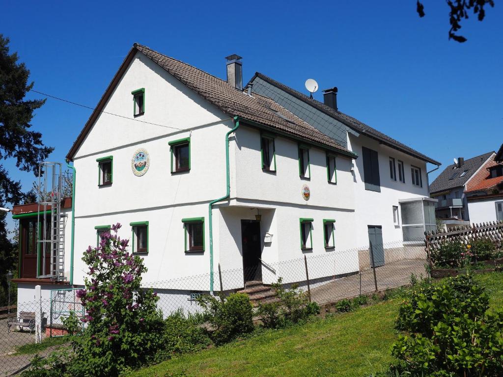 a white house with green shutters on it at Naturerlebnishaus Gaistal in Bad Herrenalb