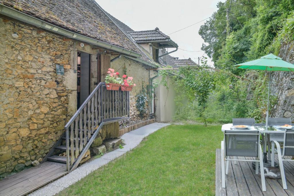 - une terrasse avec une table et un parasol à côté d'une maison dans l'établissement Le Portougais, Chalet À Chanaz, à Chanaz