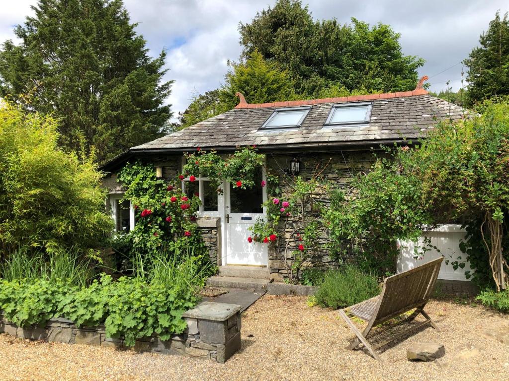 a small cottage with a white door and a bench at Gardeners Cottage in Near Sawrey