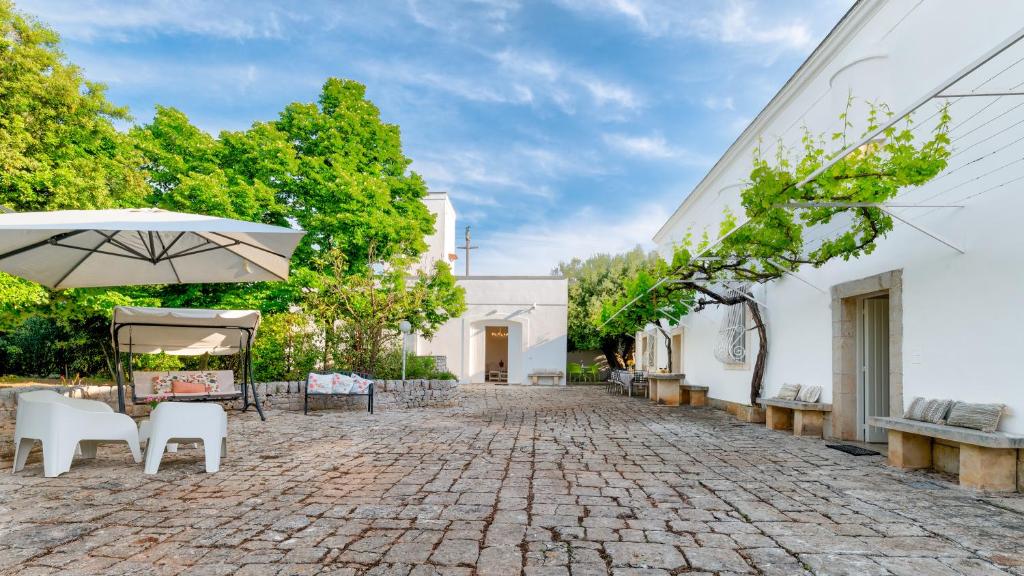 une cour avec des chaises et un parasol et un bâtiment dans l'établissement Masseria Profilo 8, Emma Villas, à Monopoli