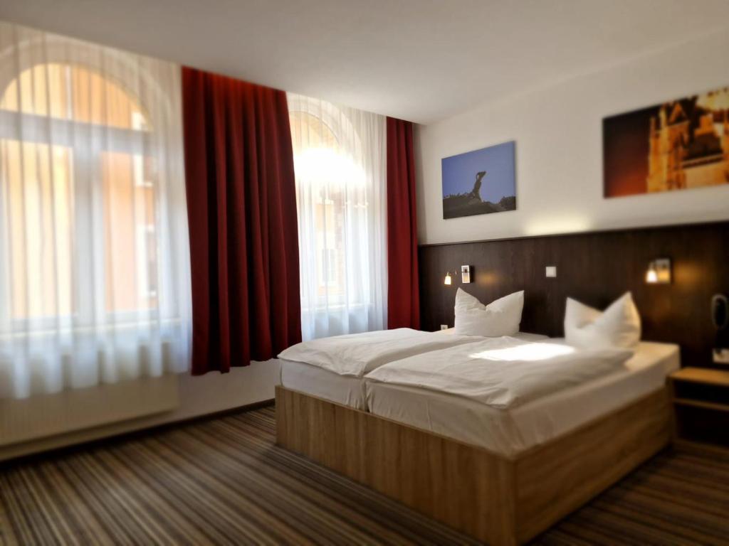 a bedroom with a large bed with white sheets at Pension bei der Marienkirche in Mühlhausen