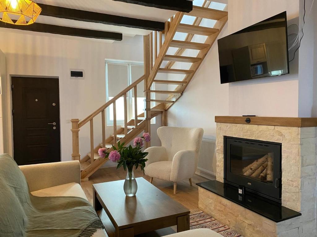 a living room with a fireplace and a tv at Casă chic La Han la Slănic in Slănic-Moldova