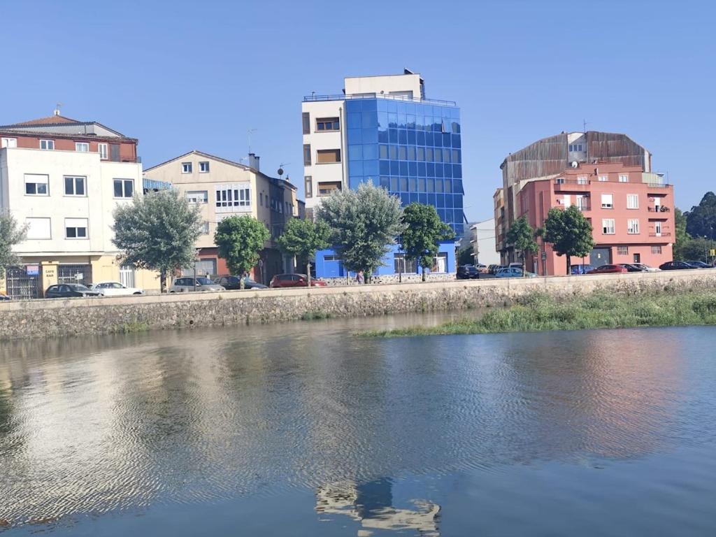 a river in a city with buildings in the background at O Pescador in Noya