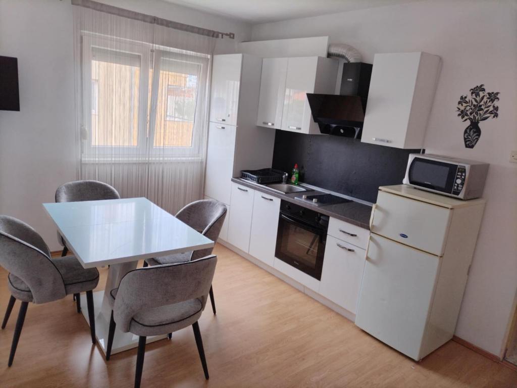 a kitchen with a white table and chairs and a table and a counter at Apartmani Punta in Zadar