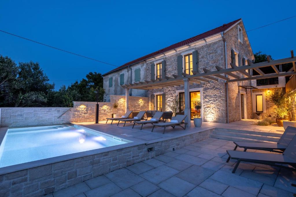 a villa with a swimming pool at night at Heritage Villa Francheza-Elegant Stone villa near the Beach, Pašman Island , Ugrinić in Ugrinići