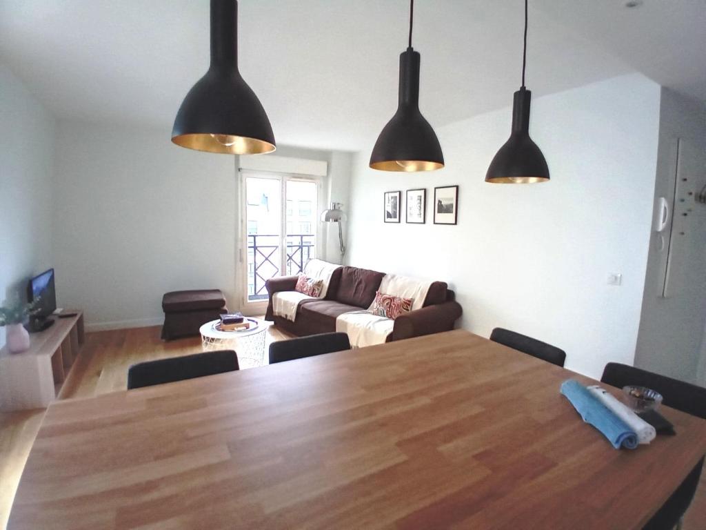 ein Wohnzimmer mit einem großen Holztisch und Lampen in der Unterkunft T3 en face de la gare, Terrasse-Rooftop, Parking in Houilles