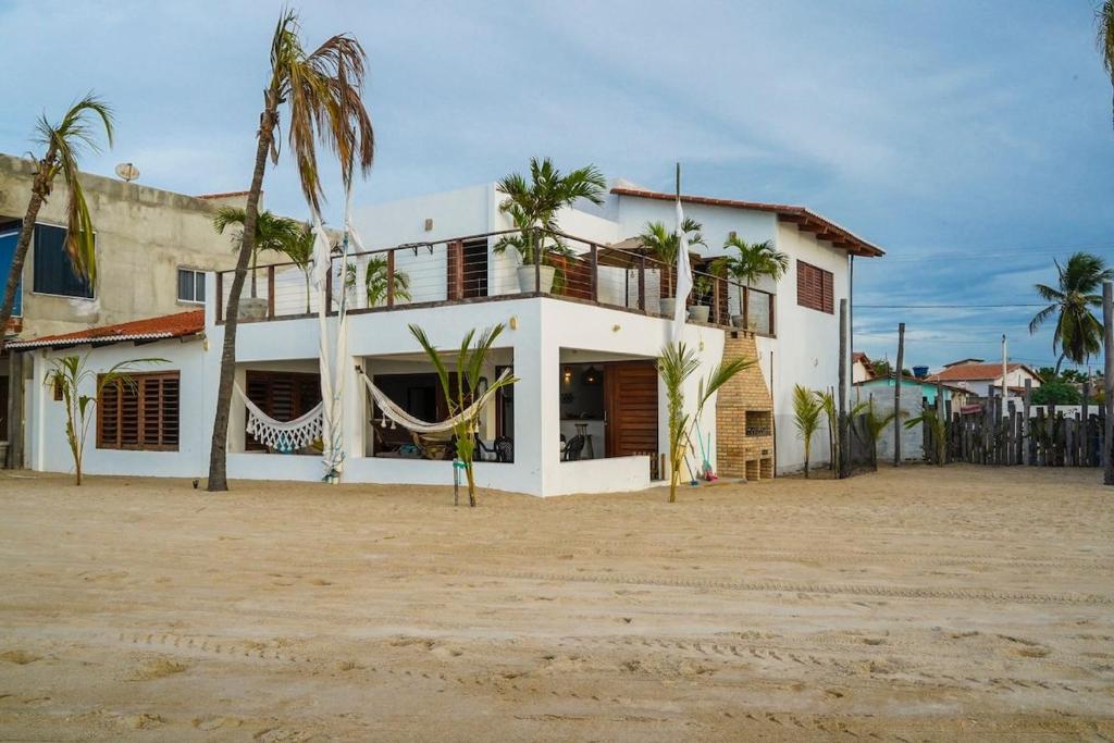 un bâtiment blanc avec des palmiers devant dans l'établissement Casa Galo Pret, à Galinhos