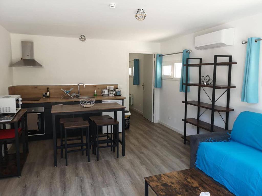a living room and kitchen with a blue couch at L'Olivier in Saint-Mitre-les-Remparts