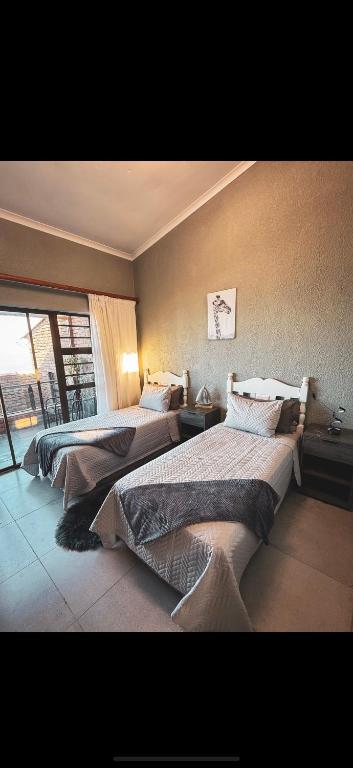 two beds in a room with a large window at Lilies & Leopards B&B in Mossel Bay