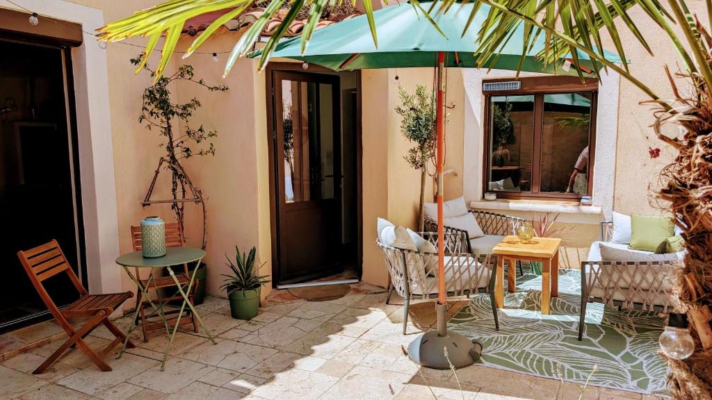 un patio avec des chaises et une table avec un parasol dans l'établissement Charming & medieval village house completely renovated with great exterior and views, à Mallemort