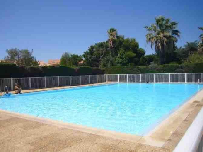 une grande piscine avec de l'eau bleue dans l'établissement Duplex T3 facing Coudoulière Beach, à Six-Fours-les-Plages