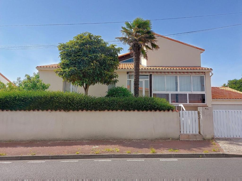 ein Haus mit einer Palme hinter einer Mauer in der Unterkunft Holiday Home La Perche by Interhome in Royan