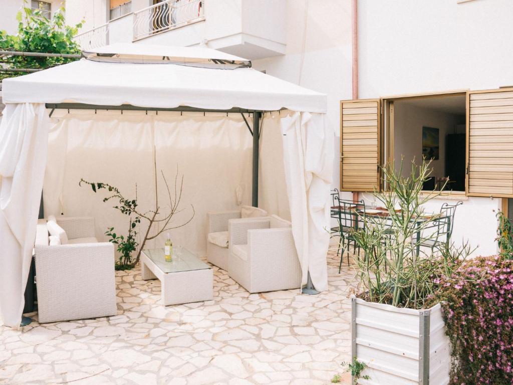 een patio met een witte parasol en stoelen en een tafel bij Apartment Rosa Dei Venti by Interhome in Santa Maria Navarrese