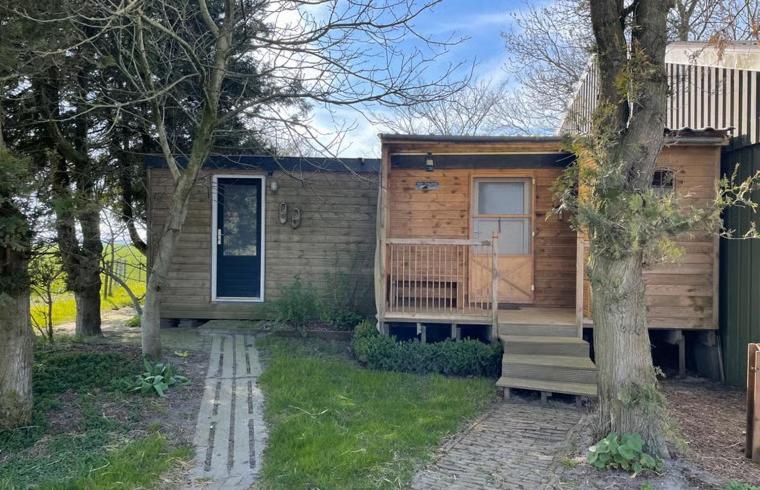 a small wooden house with a porch and a door at Chalet de Sudhoek in Vrouwenparochie