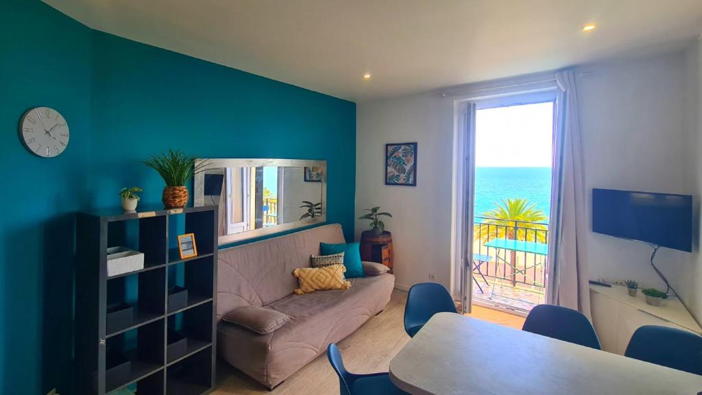 un salon avec un canapé, une table et une fenêtre dans l'établissement T2 121 Promenade Vue Mer Clim et Balcon, à Nice