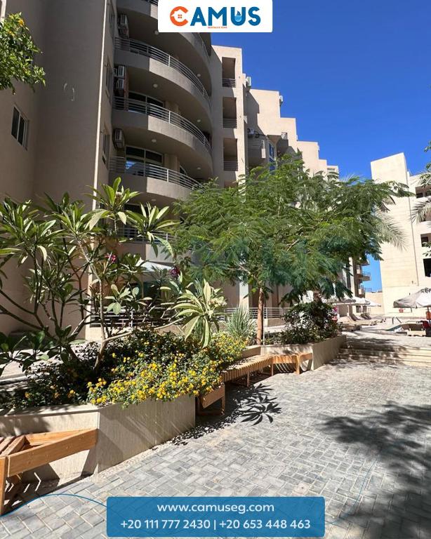 a park with benches and trees in front of a building at Princess Resort 343 in Hurghada