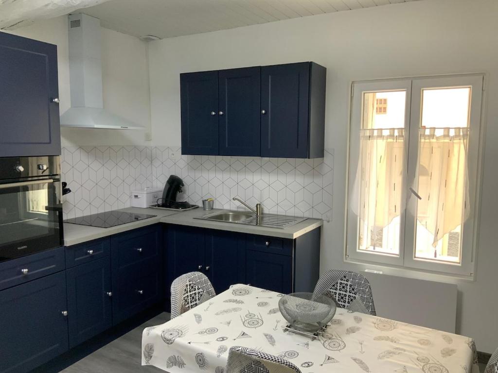 - une cuisine avec des placards bleus, une table et un évier dans l'établissement les gites de KALY, à Bélesta