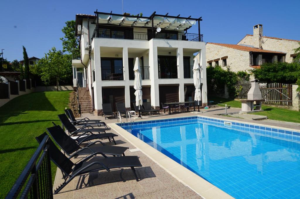 a swimming pool in front of a house with chairs at Six bedroom luxury villa with private pool in quiet residential area near beaches in Sozopol