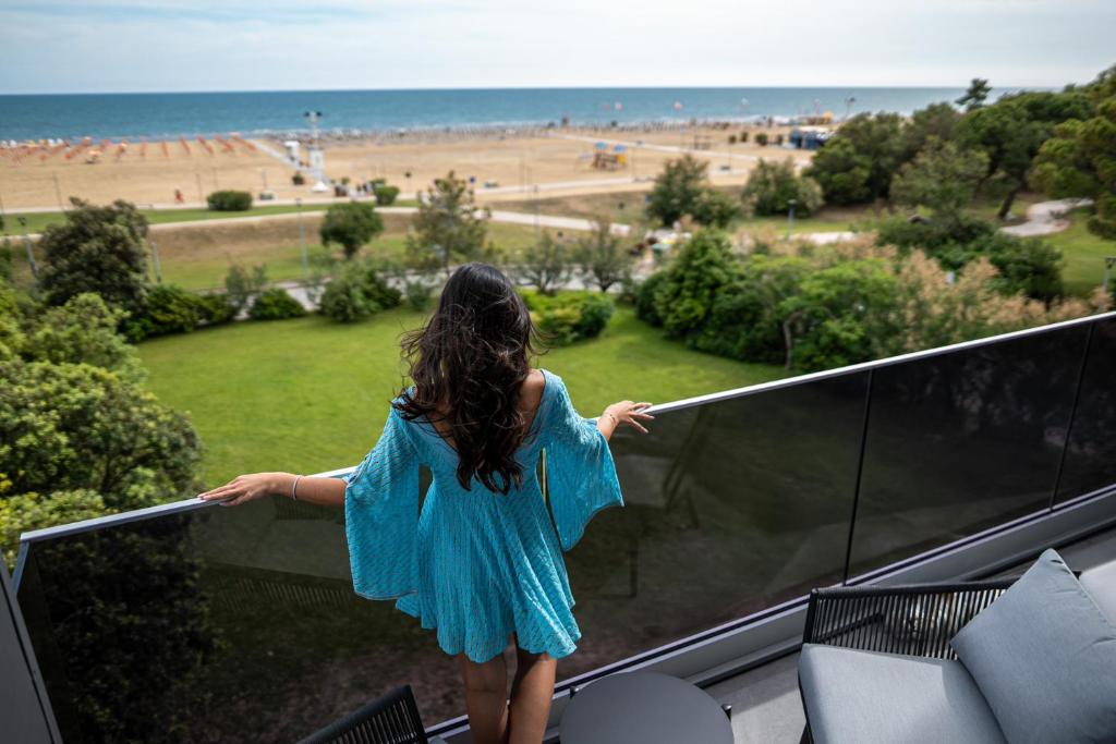 a young girl standing on a balcony looking at the beach at Residence Diana Seafront in Bibione