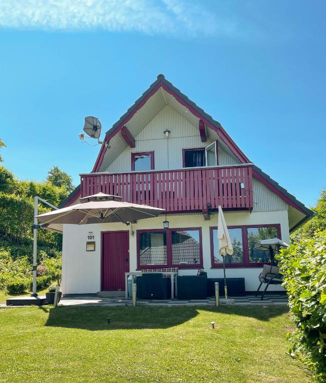 a house with a balcony and an umbrella at Ferienhaus "Gestiefelter Kater" am See im Bergland in Kirchheim