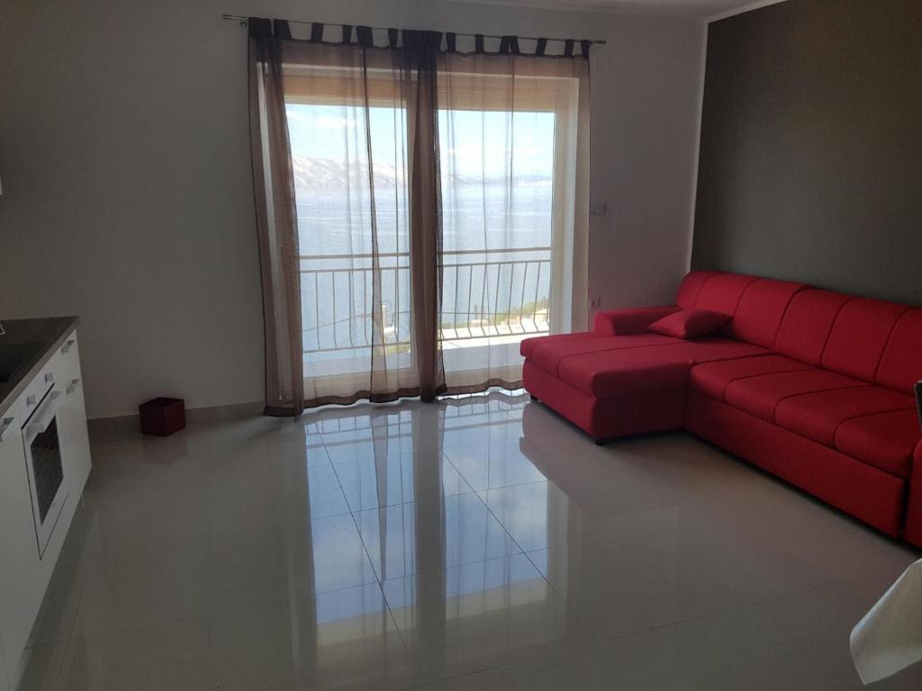 a living room with a red couch and a large window at Apartments Tereza in Senj