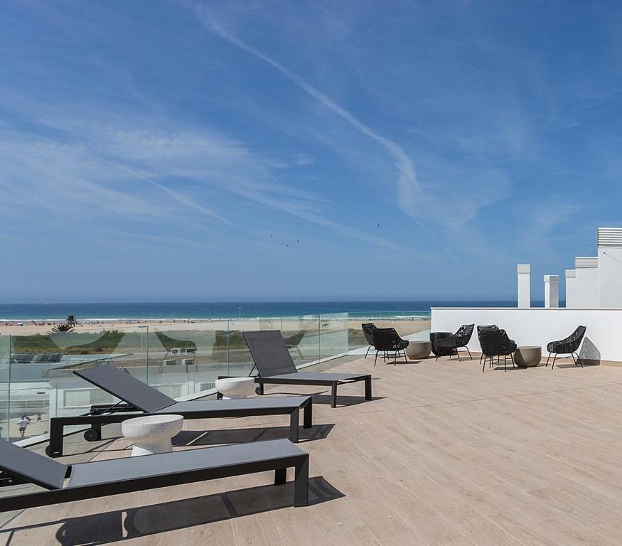 - un groupe de chaises et de tables sur la plage dans l'établissement Salitre Apartment Luxury Oceanfront with Pool Terrace and Private Parking, à Conil de la Frontera