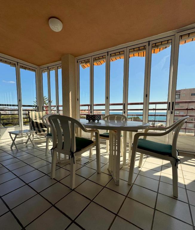a dining room with a table and chairs and windows at Tropicana in Benicàssim