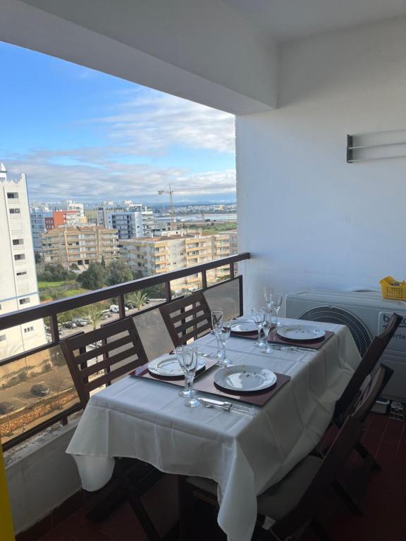 a table with plates and wine glasses on a balcony at Praia da Rocha Apartamento Costa Azul in Portimão