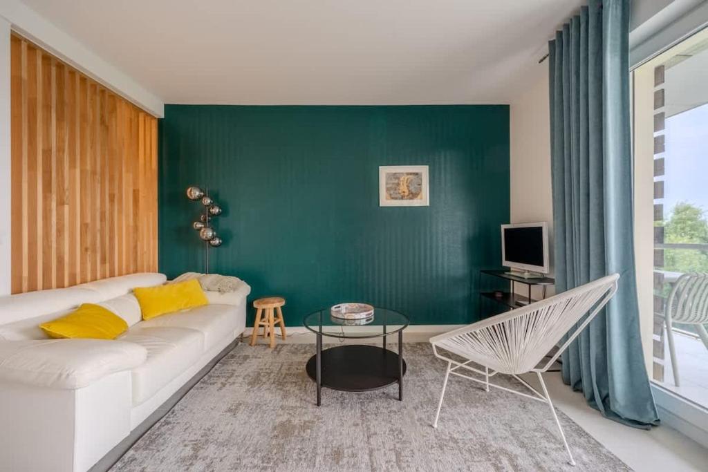 - un salon avec un canapé blanc et un mur vert dans l'établissement Les roseaux bleus, à La Rochelle