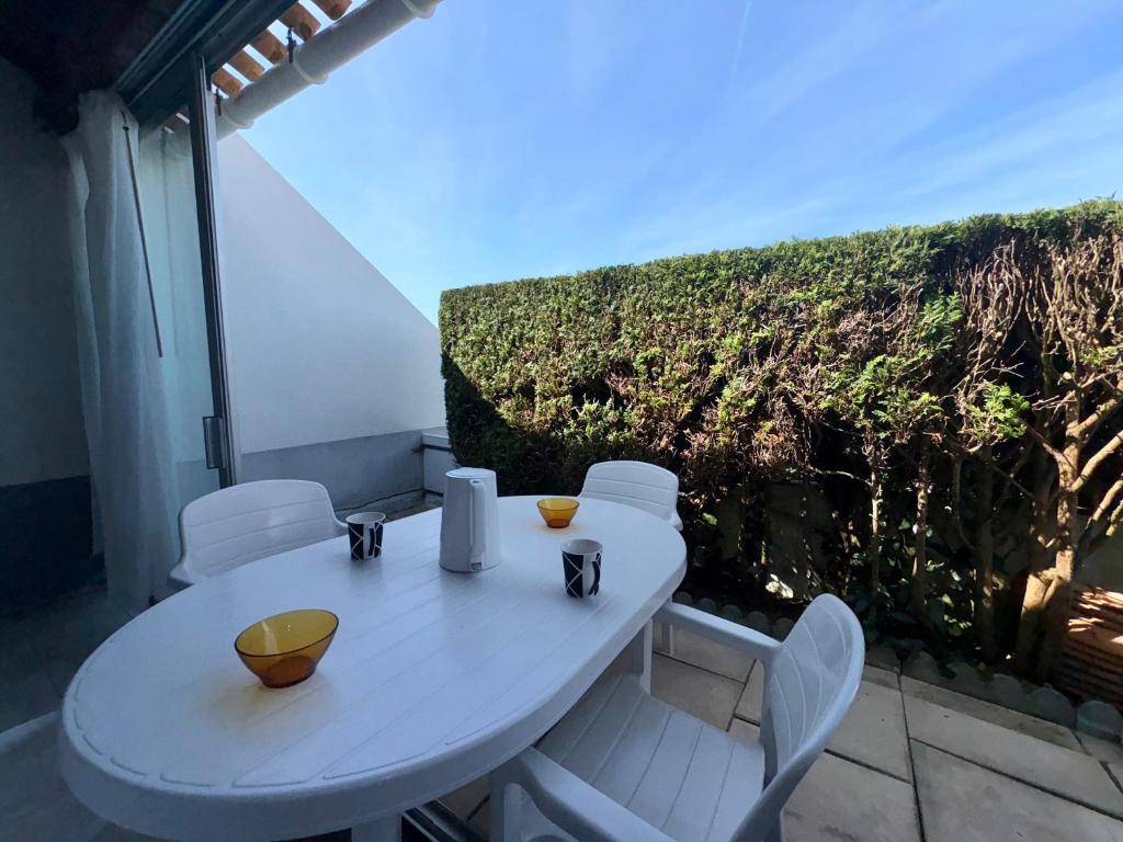 d'une table et de chaises blanches sur un balcon. dans l'établissement Maison confortable près de la forêt pour 4 personnes avec parking privatif - FR-1-323-581, à Saint-Jean-de-Monts