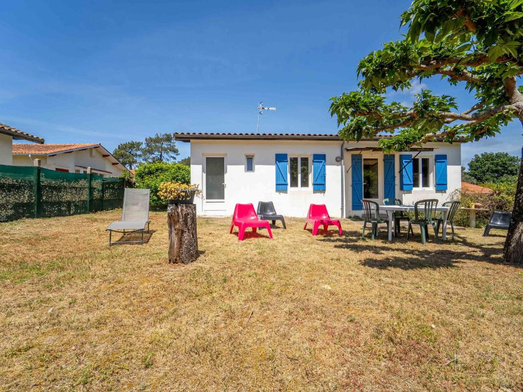 une maison avec des chaises et des tables dans la cour dans l'établissement Maison à Mimizan Plage Sud avec jardin pour 4 personnes - Ménage inclus - FR-1-50-182, à Mimizan
