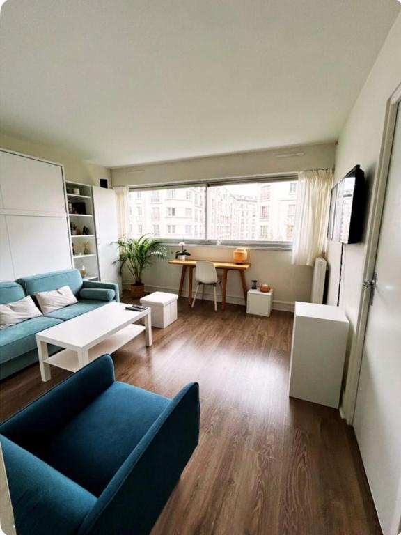 un salon avec un canapé bleu et une table dans l'établissement Cosy studio Paris 15, à Paris