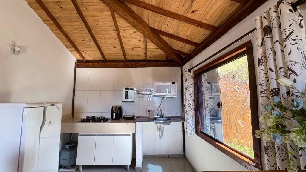 eine kleine Küche mit einem Kühlschrank und einem Fenster in der Unterkunft Loft Teto Muriquis in Nova Lima