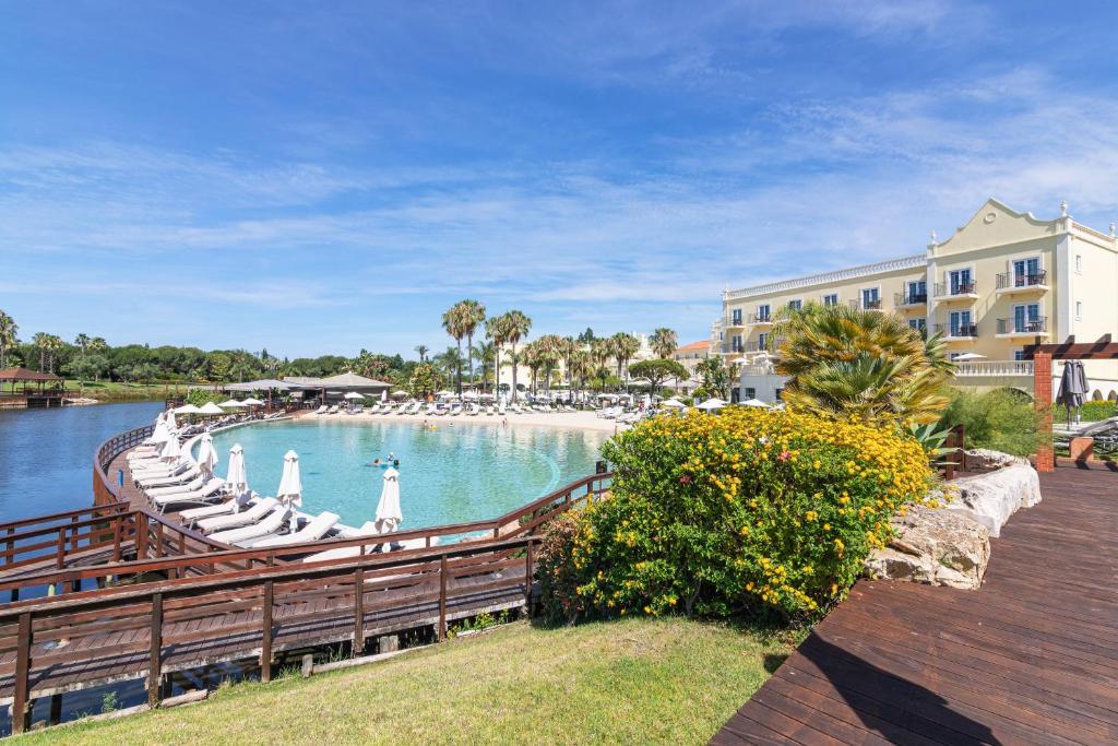 a pool with chaise lounges and chairs next to a building at Vilamoura Marina Lake in Vilamoura
