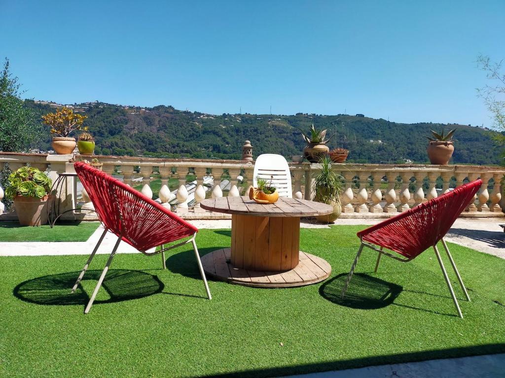 2 chaises rouges et une table dans la cour dans l'établissement Bas de villa, terrasse au calme, à Gattières