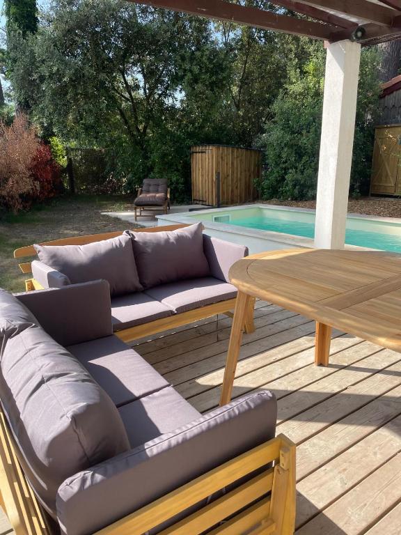 une terrasse avec un canapé, une table et une piscine dans l'établissement Villa Pyla sur Mer, à La Teste-de-Buch
