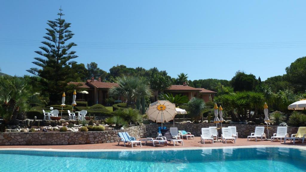 a pool with chairs and umbrellas next to a resort at Residence Cala dei Peducelli in Capoliveri