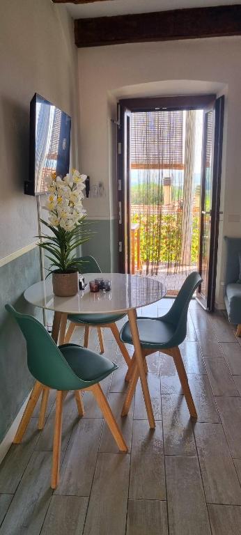 a dining room with a glass table and two green chairs at Casa Enzo in Besozzo