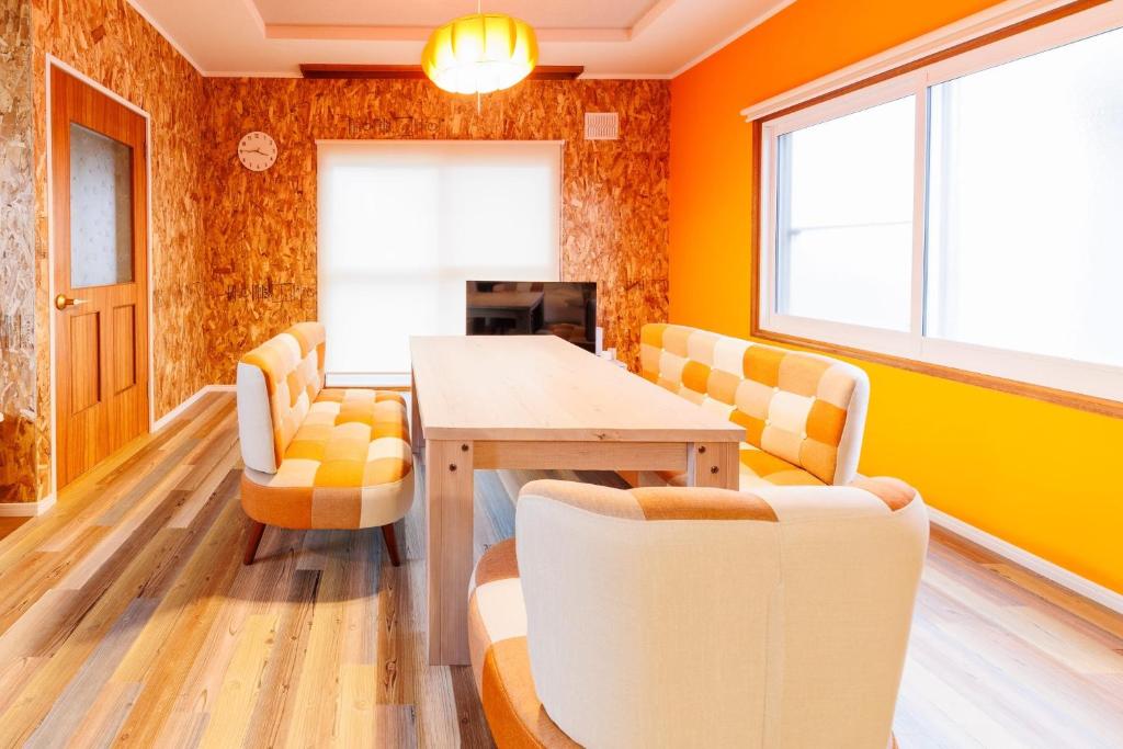 a dining room with orange walls and a table and chairs at Biei Yume Yume House - Vacation STAY 38543v in Biei