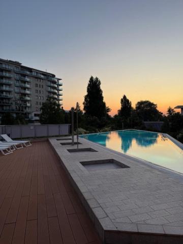 a large swimming pool with a sunset in the background at Amada Apartment in Budapest