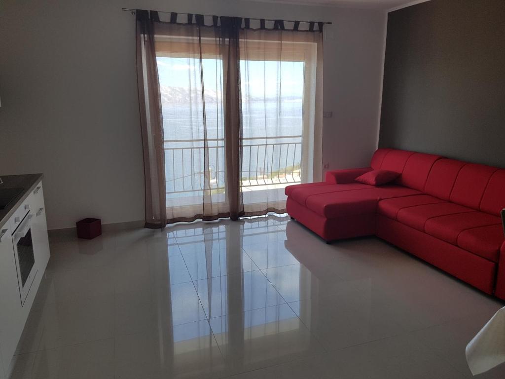 a living room with a red couch and a large window at Apartments Tereza in Senj