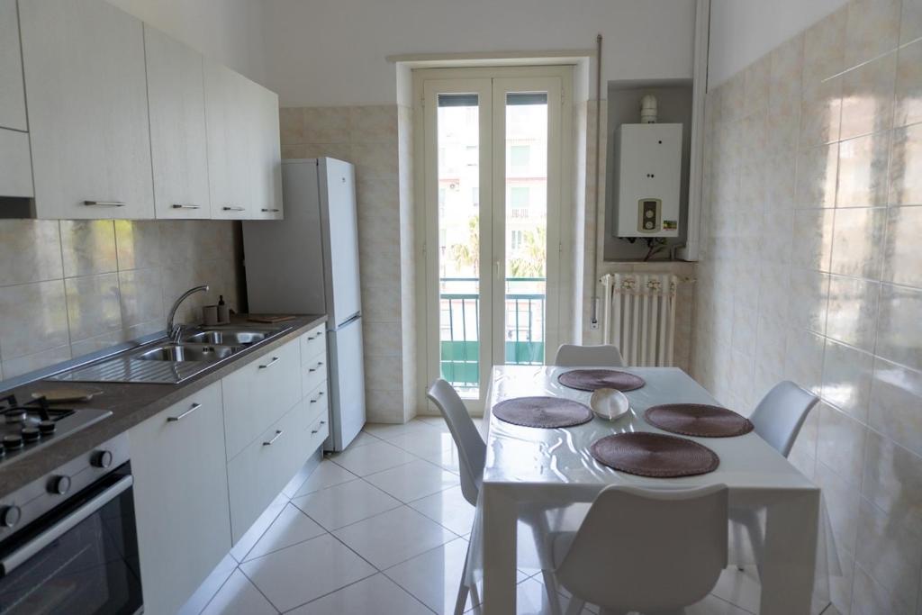 a white kitchen with a table and chairs and a sink at Luma Casa Vacanze in Gaeta