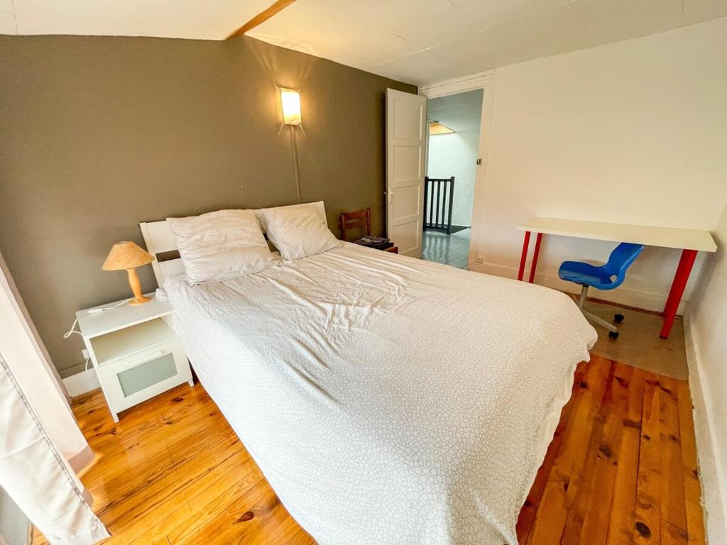 une chambre avec un lit blanc et un parquet dans l'établissement Le Saint'& Color - WIFI - close to city center - T3, à Saint-Étienne