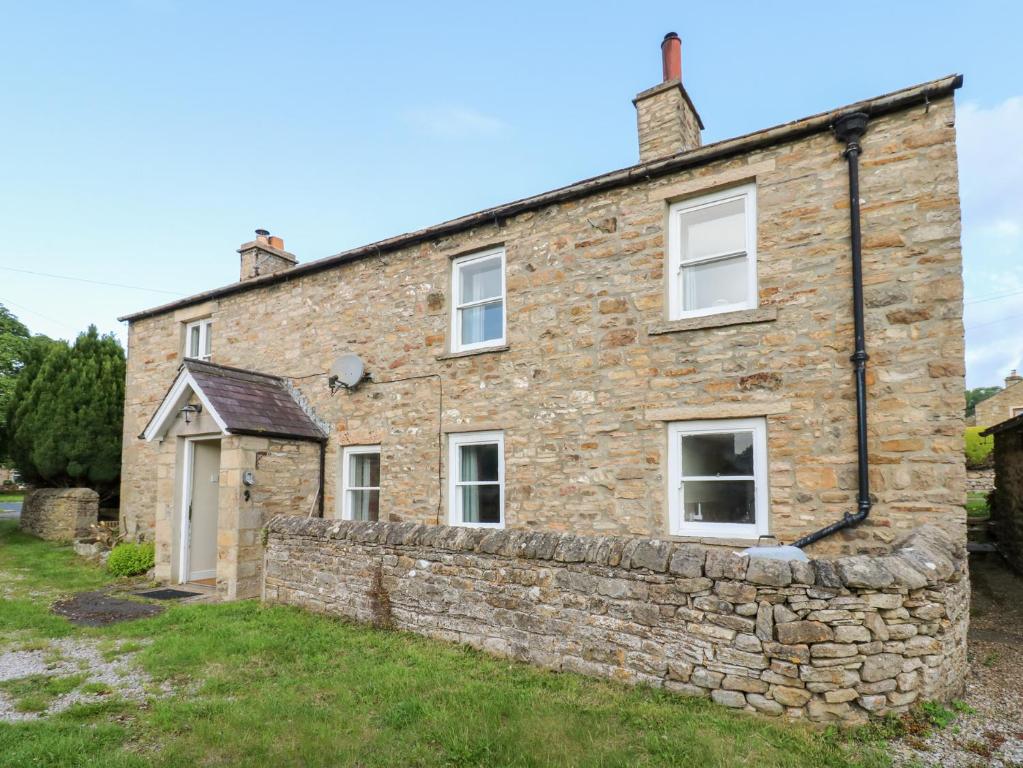 an old stone house with a stone wall at Rosemary Cottage in Leyburn