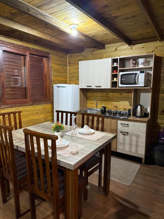 a kitchen with a table and chairs in a cabin at Vila Vicença Natural Refuge in Praia Grande