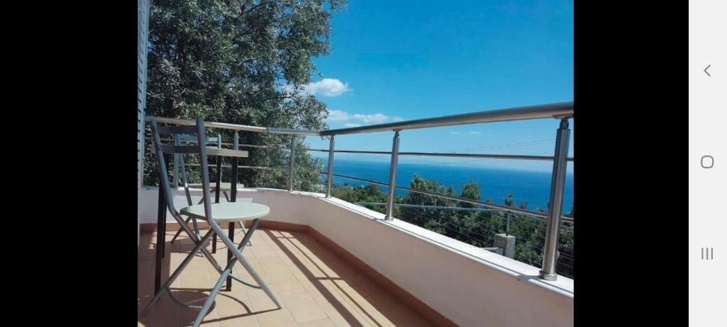 a balcony with a chair and a view of the ocean at Manas Rooms in Dhërmi
