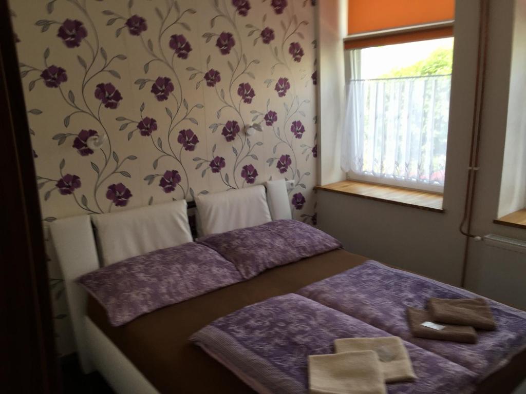 a bedroom with a bed with purple sheets and a window at Penzion Pálava in Nové Mlýny